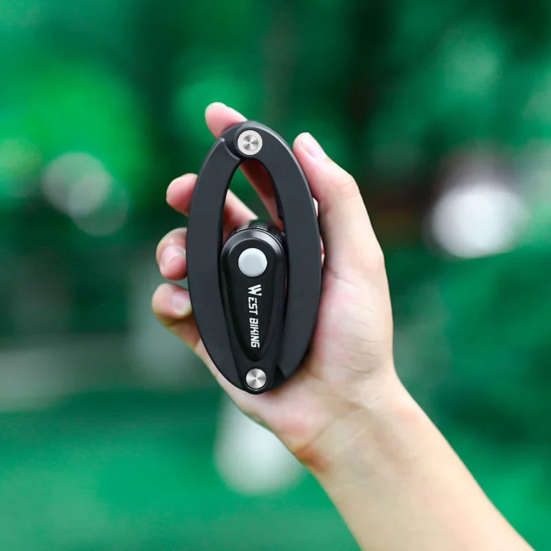 Hand holding compact West Biking foldable bike lock, urban cycling safety gear outdoors